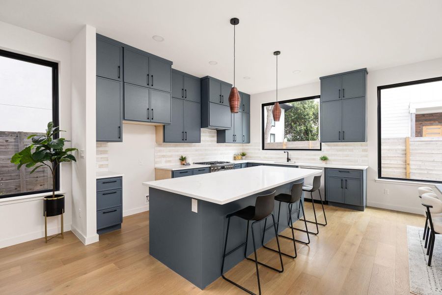 A vibrant kitchen features a grand island, sleek cabinetry, and a bright, open atmosphere.