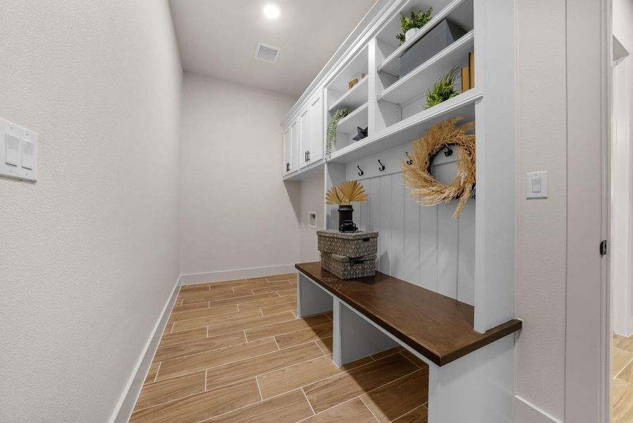 Functional mudroom featuring built-in shelving, practical hooks, and a comfortable bench seating area.