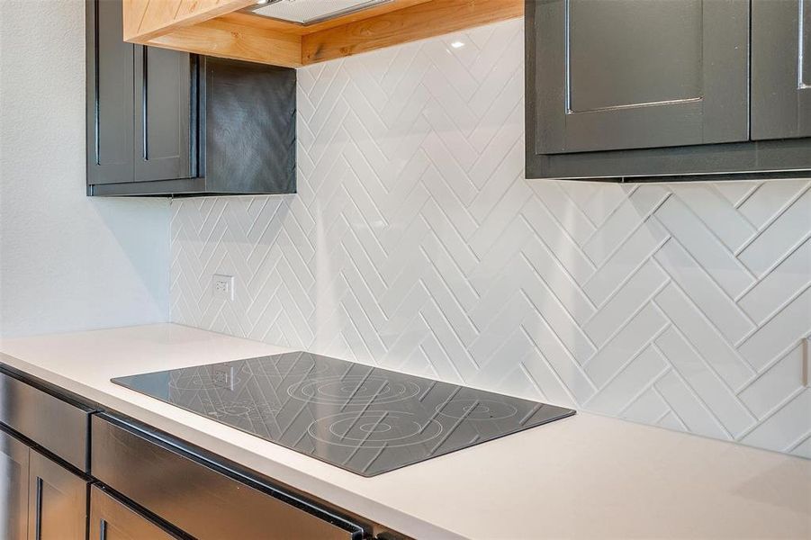 Kitchen with backsplash and black electric cooktop