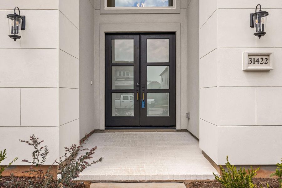 Grand front entryway making a striking first impression with a contemporary flair. Dramatic, oversized double front doors feature black iron trim and large, frosted multi-lite glass panels that provide both privacy and excellent interior light transmission. Grand front entryway making a striking first impression with a contemporary flair. Dramatic, oversized double front doors feature black iron trim and large, frosted multi-lite glass panels that provide both privacy and excellent interior light transmission.