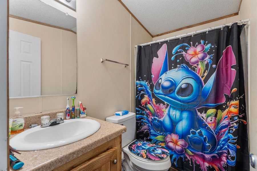 Bathroom featuring vanity, toilet, ornamental molding, and a textured ceiling Bathroom featuring vanity, toilet, ornamental molding, and a textured ceiling