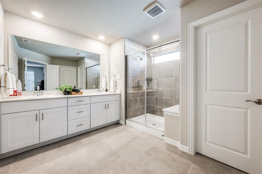 Full bathroom featuring double vanity, a shower stall, light tile patterned floors, and recessed lighting Full bathroom featuring double vanity, a shower stall, light tile patterned floors, and recessed lighting