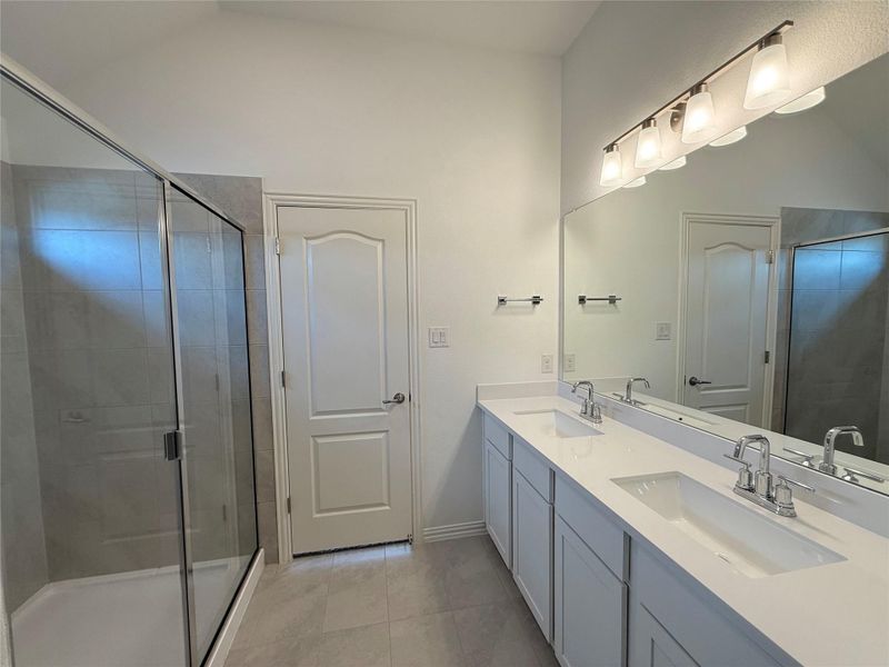 Full bath featuring a stall shower, double vanity, and light tile patterned floors Full bath featuring a stall shower, double vanity, and light tile patterned floors
