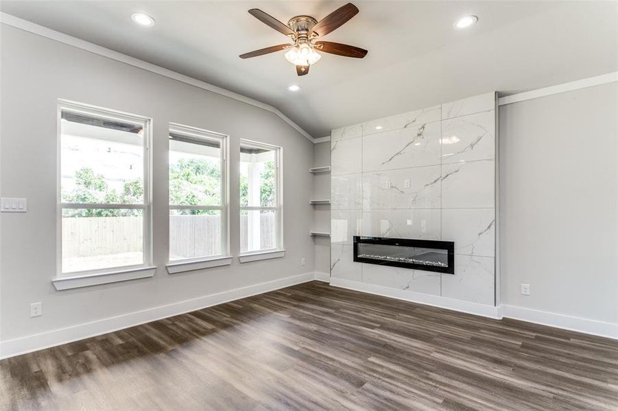 Unfurnished living room featuring a tile fireplace, dark hardwood / wood-style floors, ceiling fan, and lofted ceiling