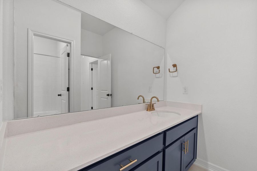 The secondary bath features tile flooring, custom stained cabinetry and light countertops and a shower/tub combo. Perfect for accommodating any visiting family and friends.