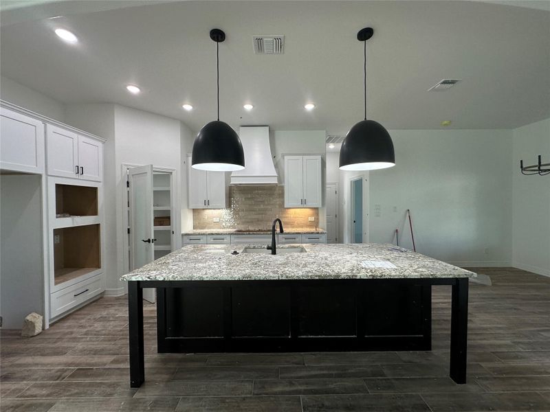 Kitchen with a kitchen bar, dark cabinets, backsplash, white cabinets, and recessed lighting