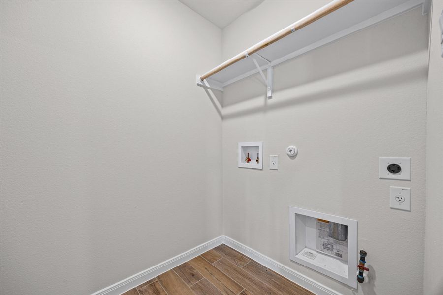 A dedicated utility space includes wood-look tile flooring and hookups ready for laundry appliances. A dedicated utility space includes wood-look tile flooring and hookups ready for laundry appliances.