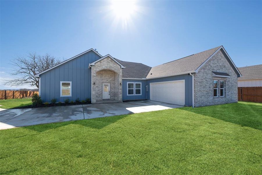 Ranch-style home featuring a garage and a front lawn