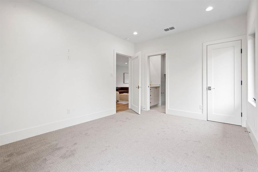Unfurnished bedroom with recessed lighting, light carpet, and ensuite bath Unfurnished bedroom with recessed lighting, light carpet, and ensuite bath
