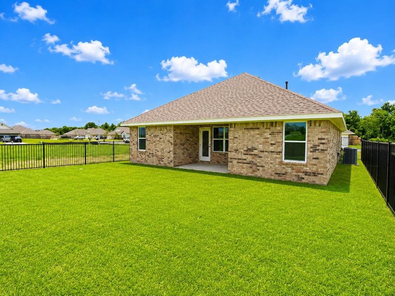 Spacious backyard with lush green space, black metal fencing, and plenty of room for outdoor entertaining and relaxation. Spacious backyard with lush green space, black metal fencing, and plenty of room for outdoor entertaining and relaxation.