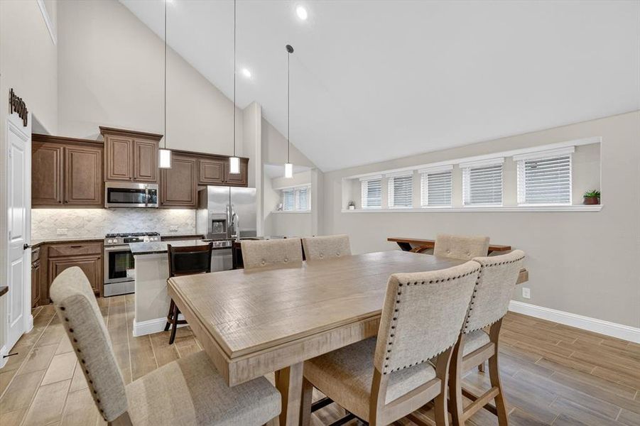 Spacious dining area with vaulted ceilings and wood-finish flooring Spacious dining area with vaulted ceilings and wood-finish flooring