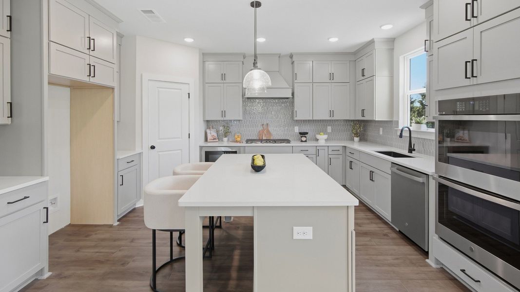 Kitchen with island and plenty of cabinets for convenient storage space next to pantry door