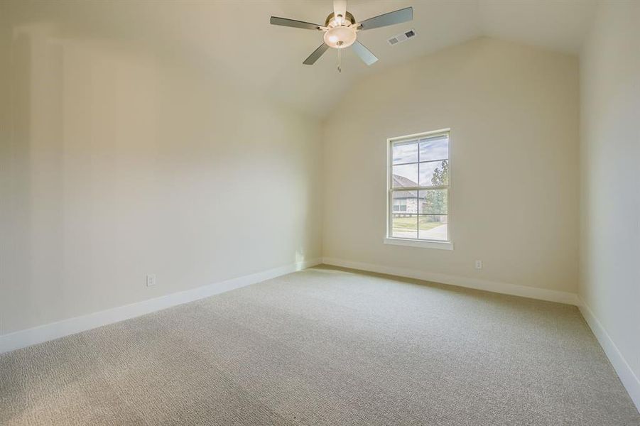 Carpeted spare room with vaulted ceiling and a ceiling fan Carpeted spare room with vaulted ceiling and a ceiling fan