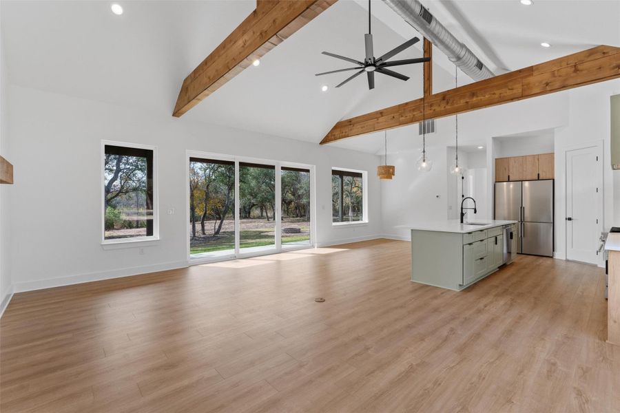 Seamless open living, kitchen, and dining with vaulted ceilings, exposed beams, and expansive sliders that open to lush outdoor views Seamless open living, kitchen, and dining with vaulted ceilings, exposed beams, and expansive sliders that open to lush outdoor views