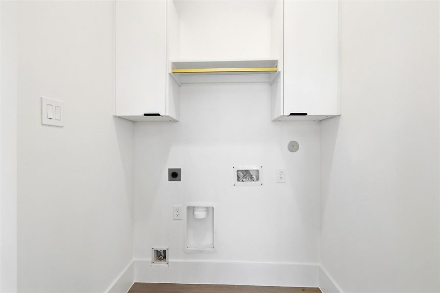 Same floorplan - different finishes. Dedicated laundry room featuring custom upper cabinetry and a built-in brass hanging rod above the appliance hookups.