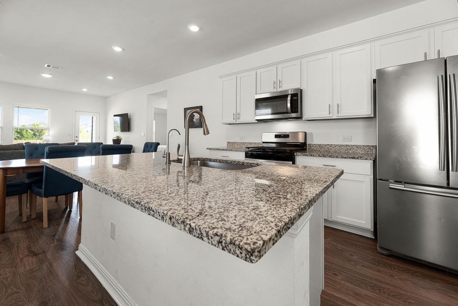 Kitchen with stainless steel appliances, dark stone counters, white cabinets, dark wood-type flooring, and recessed lighting