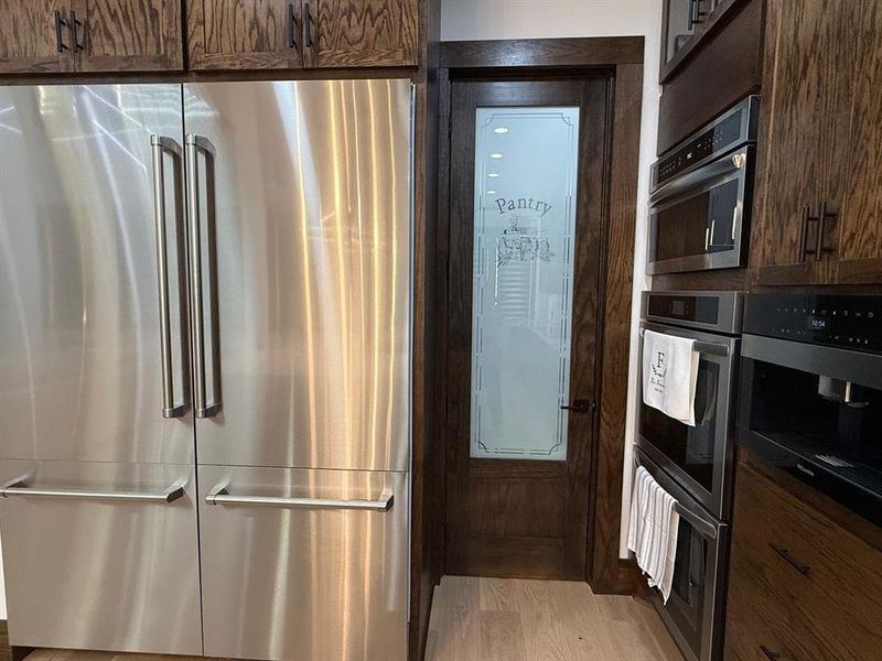 Kitchen featuring appliances with stainless steel finishes, light wood-style flooring, and dark brown cabinetry