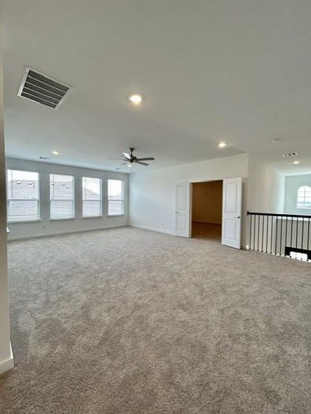 Spacious carpeted room featuring multiple windows, recessed lighting, and a ceiling fan Spacious carpeted room featuring multiple windows, recessed lighting, and a ceiling fan