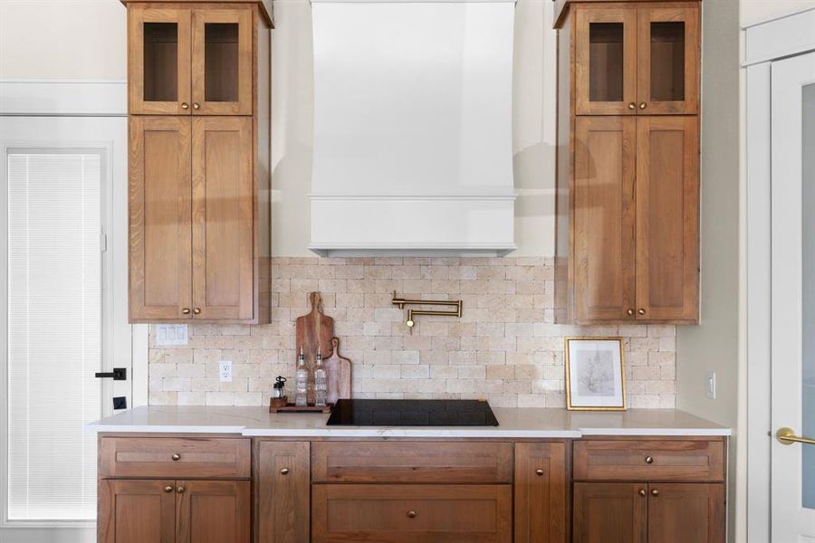 Kitchen featuring black electric stovetop, tasteful backsplash, and exhaust hood