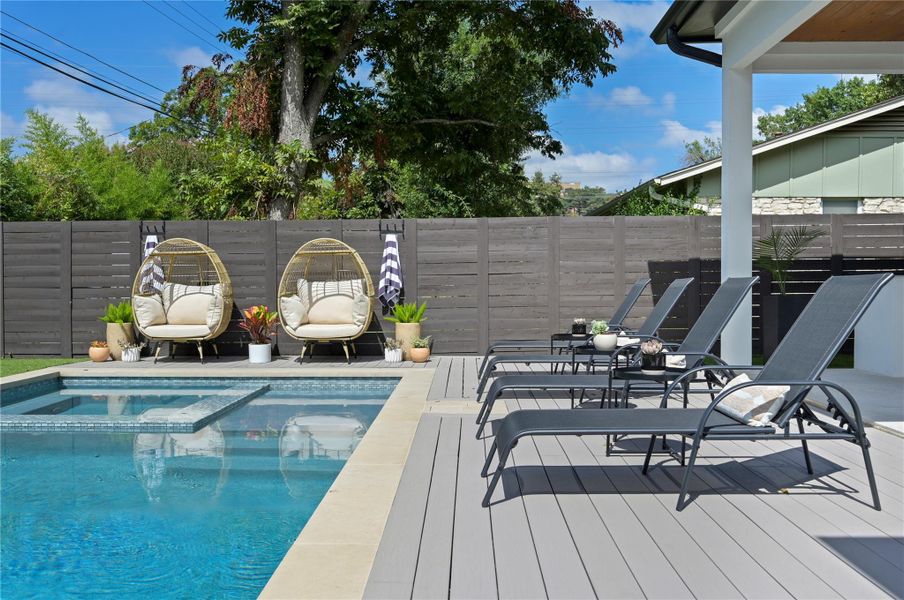 View of pool featuring fence, a pool with connected hot tub, and a wooden deck