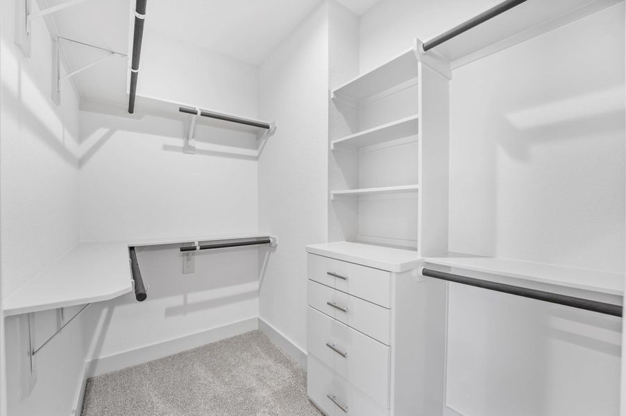 This photo shows a spacious walk-in closet featuring multiple white shelves, hanging rods, and a built-in drawer unit, perfect for organized storage. This photo shows a spacious walk-in closet featuring multiple white shelves, hanging rods, and a built-in drawer unit, perfect for organized storage.