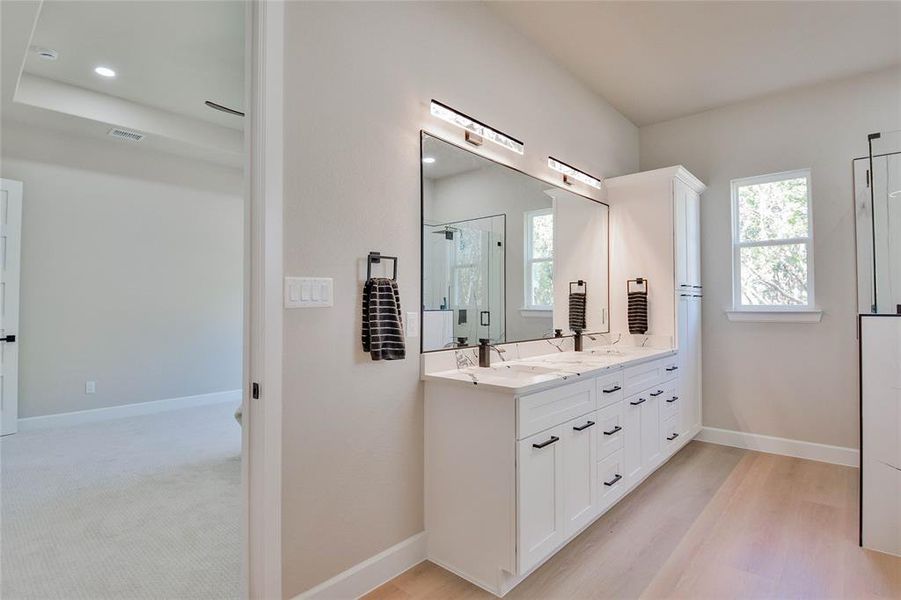 Bathroom featuring a shower stall, double vanity, light wood-style floors, and recessed lighting Bathroom featuring a shower stall, double vanity, light wood-style floors, and recessed lighting