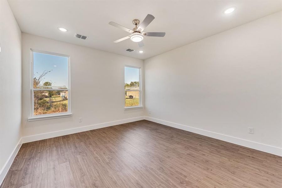 Empty room featuring plenty of natural light, wood-type flooring, and ceiling fan