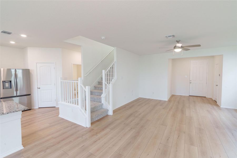 A spacious, open-concept living area with light-toned hardwood flooring and a stylish staircase. A spacious, open-concept living area with light-toned hardwood flooring and a stylish staircase.