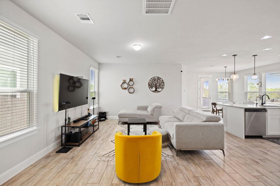 Living area with baseboards, visible vents, light wood-style flooring, and recessed lighting Living area with baseboards, visible vents, light wood-style flooring, and recessed lighting