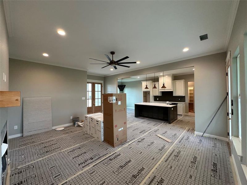 Kitchen with ceiling fan, crown molding, pendant lighting, a center island, and white cabinetry