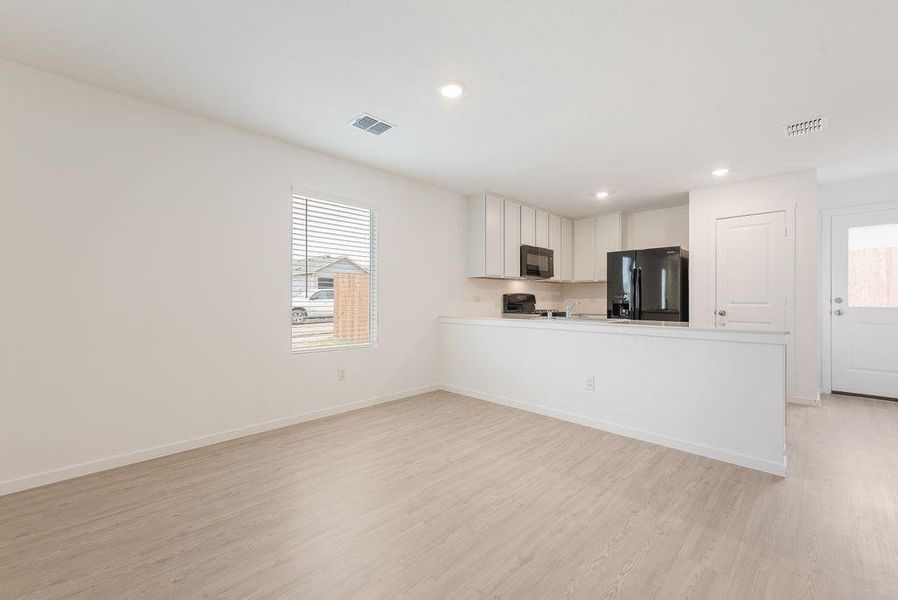 Kitchen featuring light hardwood / wood-style floors, black appliances, kitchen peninsula, and white cabinets