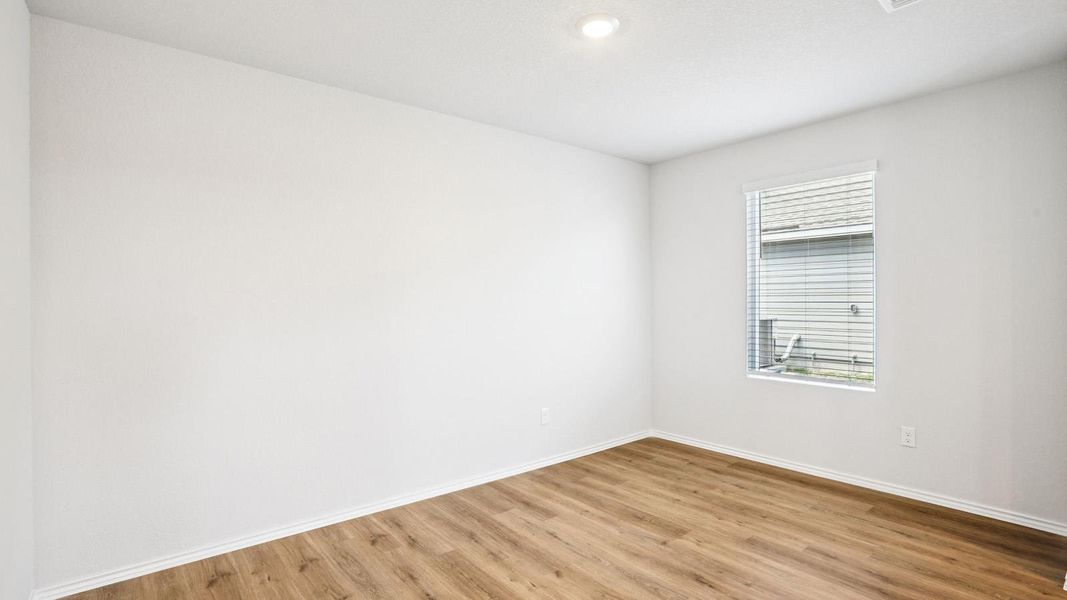 Bright room featuring wood-finish flooring, white walls, and a recessed ceiling light