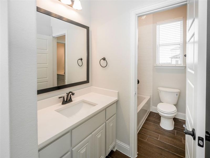 Full bath featuring wood finish floors, vanity, and washtub / shower combination