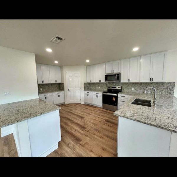 A contemporary kitchen showcasing ample white cabinetry and sleek granite countertops, perfect for culinary endeavors.