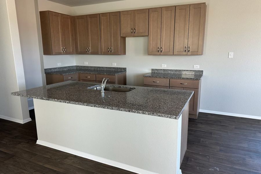 Image of home kitchen with light brown cabinets, center island, wood-look floors, and white walls Image of home kitchen with light brown cabinets, center island, wood-look floors, and white walls