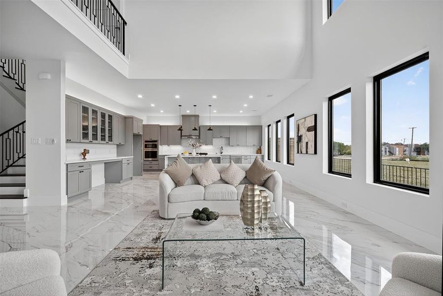 Living area featuring a towering ceiling, light marble finish flooring, built in study area, recessed lighting, and stairway