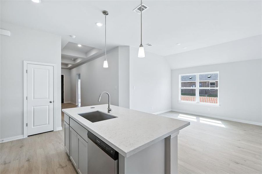 Kitchen with light wood-style flooring, dishwasher, open floor plan, decorative light fixtures, and gray cabinets Kitchen with light wood-style flooring, dishwasher, open floor plan, decorative light fixtures, and gray cabinets