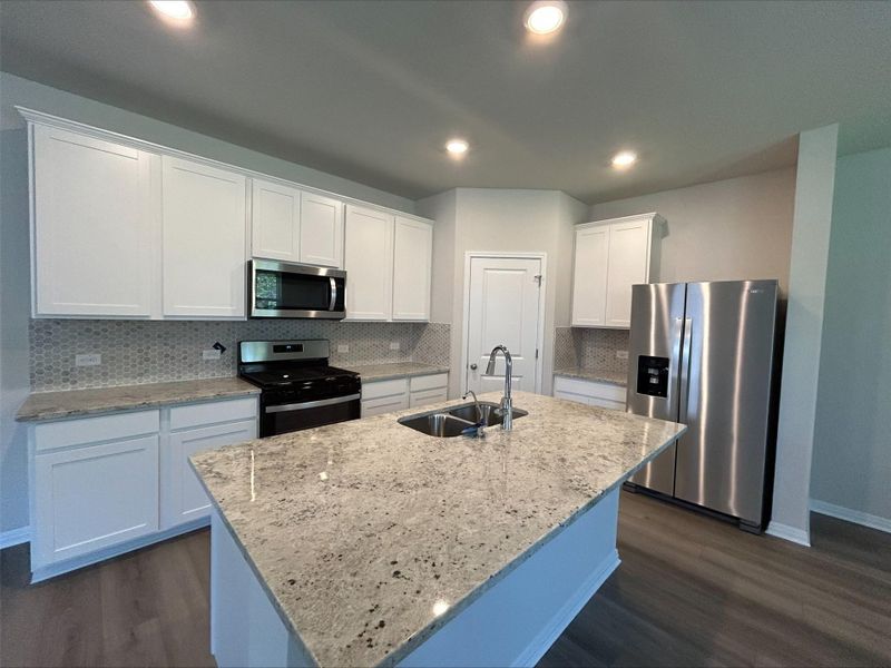 Kitchen featuring appliances with stainless steel finishes, dark wood-style flooring, white cabinetry, tasteful backsplash, and recessed lighting