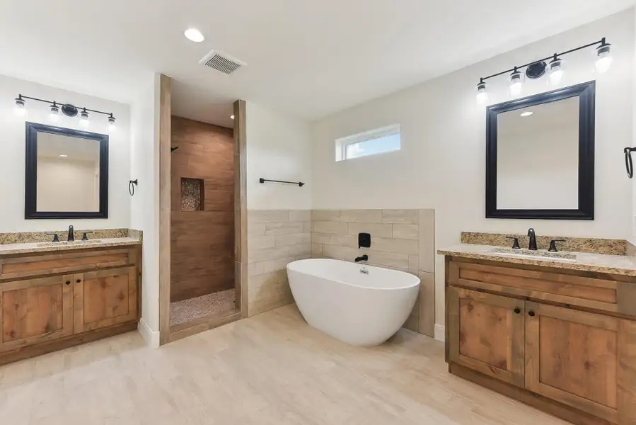 Full bathroom featuring a sink, a freestanding bath, a tile shower, two vanities, and visible vents