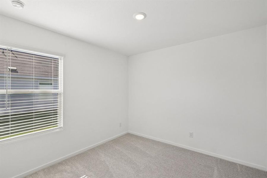 Carpeted spare room with a smoke detector and recessed lighting