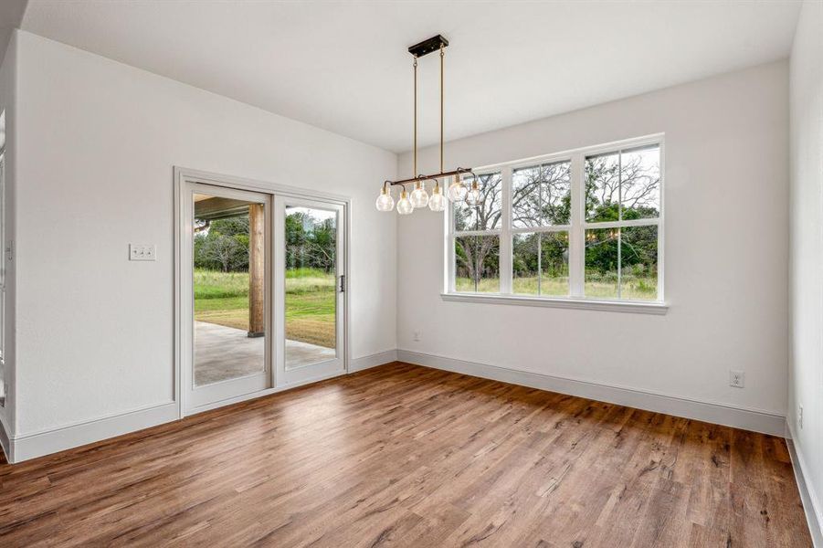 Unfurnished dining area with hardwood / wood-style flooring, a healthy amount of sunlight, and a chandelier