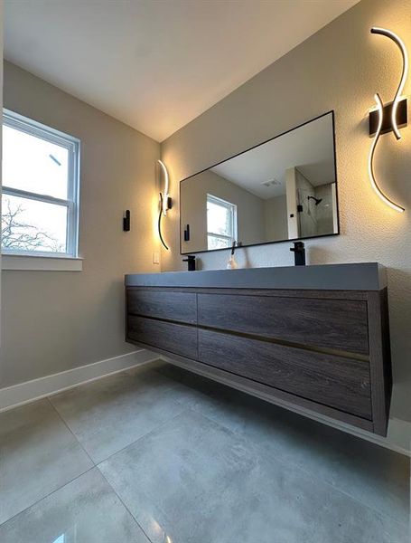 Bathroom with concrete flooring, vanity, and walk in shower