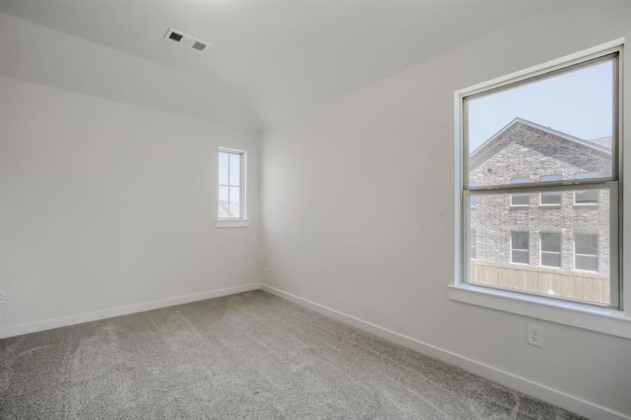 Light-filled room featuring neutral wall tones, gray carpeting, a large double-hung window, a smaller vertical window, and white trim throughout