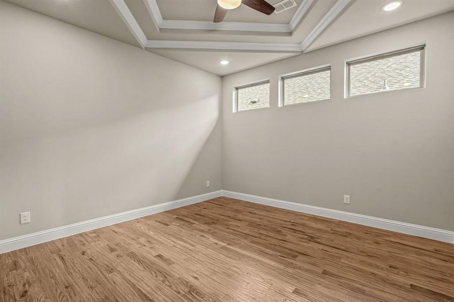 Empty room featuring wood finished floors, a tray ceiling, ceiling fan, recessed lighting, and crown molding