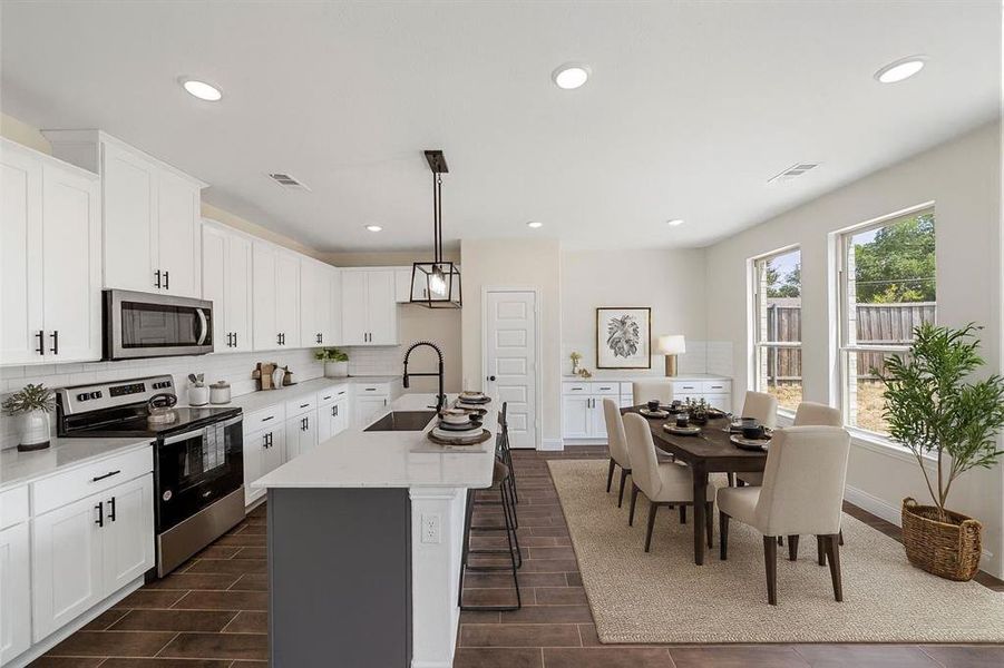 Kitchen featuring appliances with stainless steel finishes, decorative backsplash, white cabinetry, an island with sink, and recessed lighting VS Kitchen featuring appliances with stainless steel finishes, decorative backsplash, white cabinetry, an island with sink, and recessed lighting VS