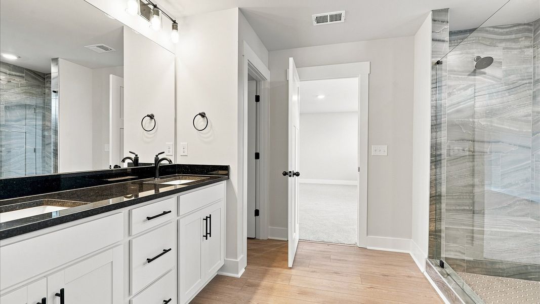 Accomplished design shines in this primary bath with dual vanity and a sleek walk-in shower