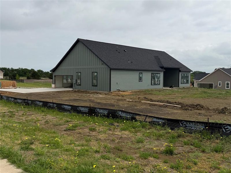 Back of property with board and batten siding, roof with shingles, and a garage Back of property with board and batten siding, roof with shingles, and a garage