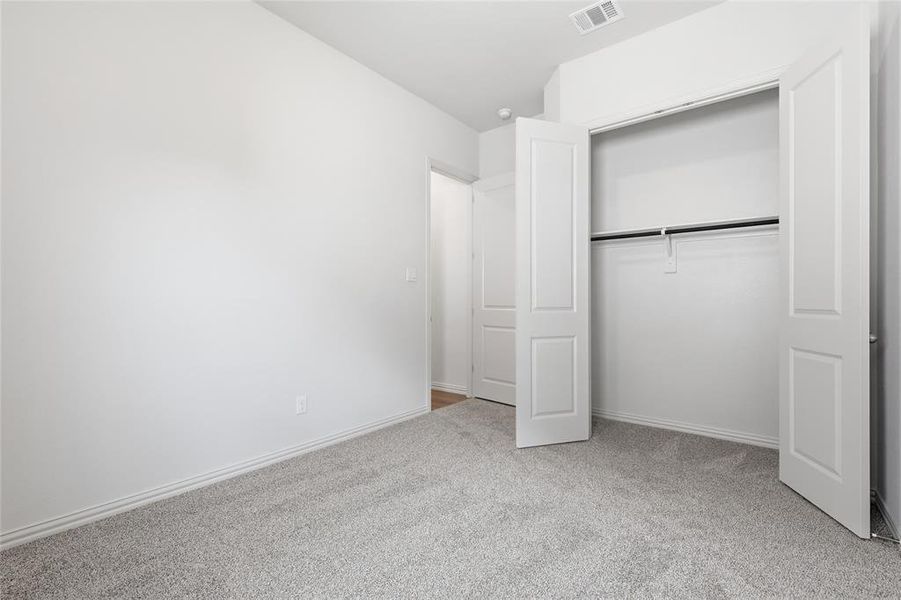 Unfurnished bedroom featuring light carpet and a closet