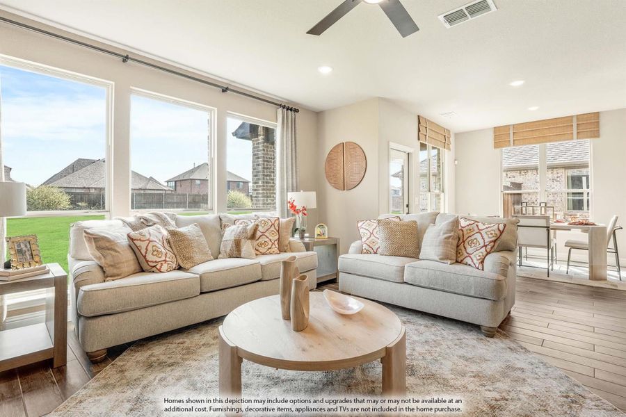 Bright living room with two beige sofas, wood coffee table, ceiling fan, and large windows overlooking a backyard Bright living room with two beige sofas, wood coffee table, ceiling fan, and large windows overlooking a backyard