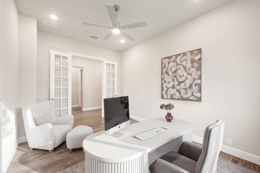 Home office with white curved desk, computer, ceiling fan, and French doors on hardwood floors